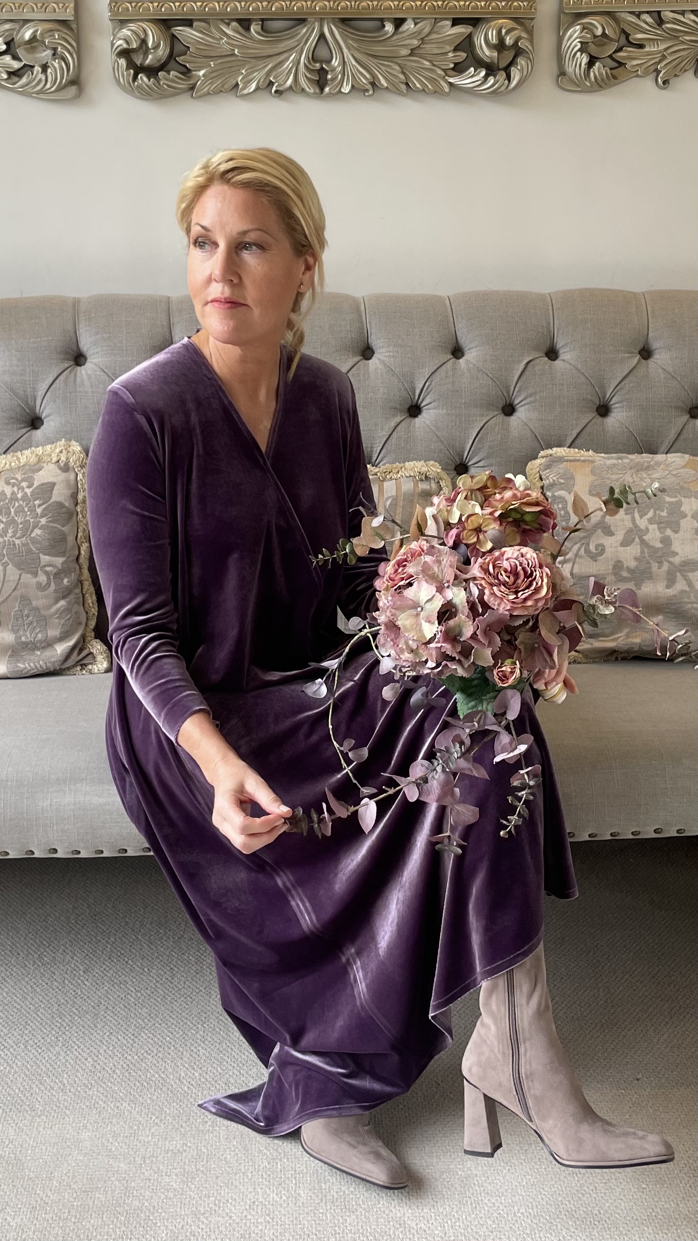 model sitting wearing velvet dress and holdong flowers