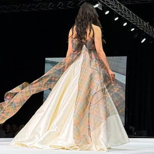 Model walking on the catwalk in ivory wedding dress with buchanan tartan organza bow anfd tiers